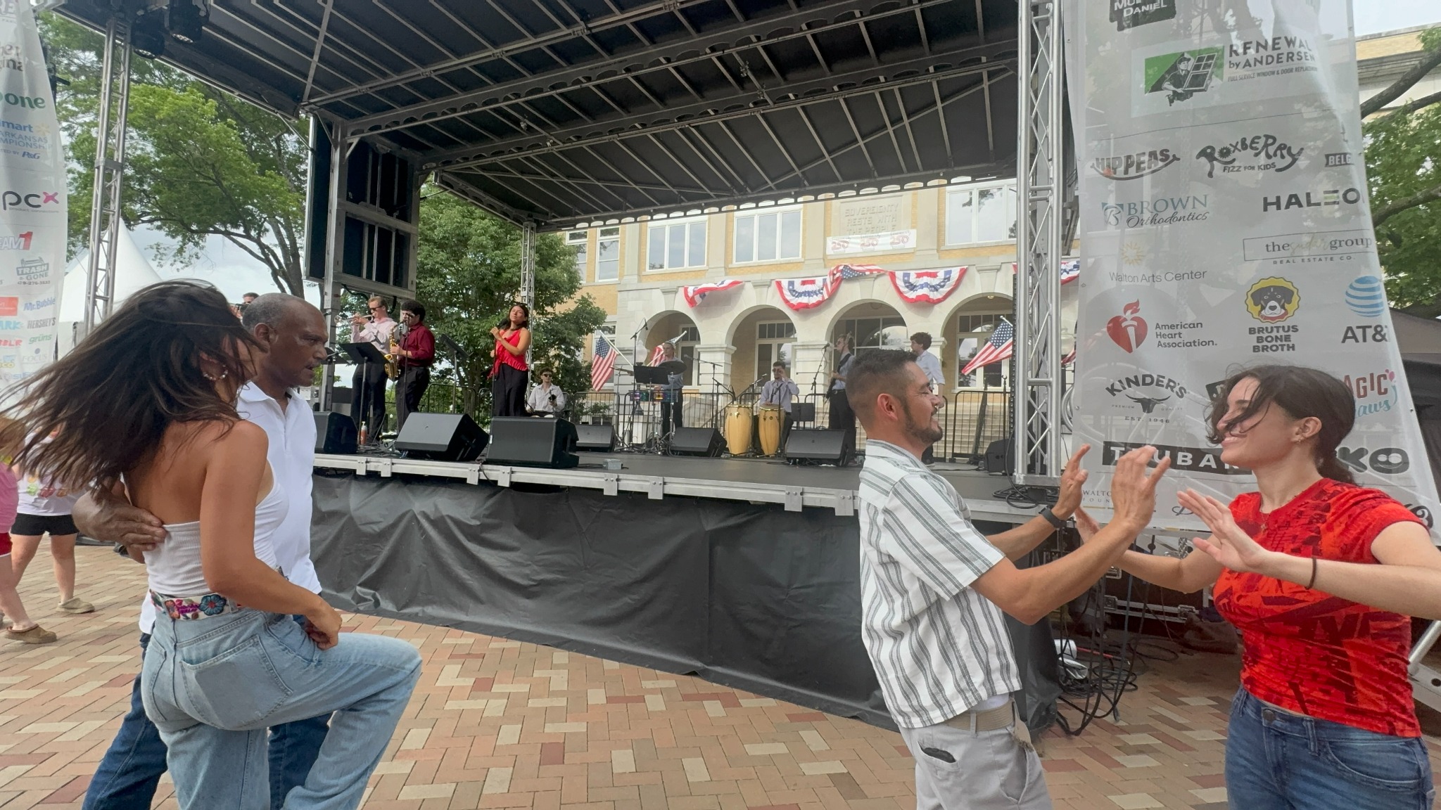 Couples dancing in front of Orquesta Afinke at an outdoor festival